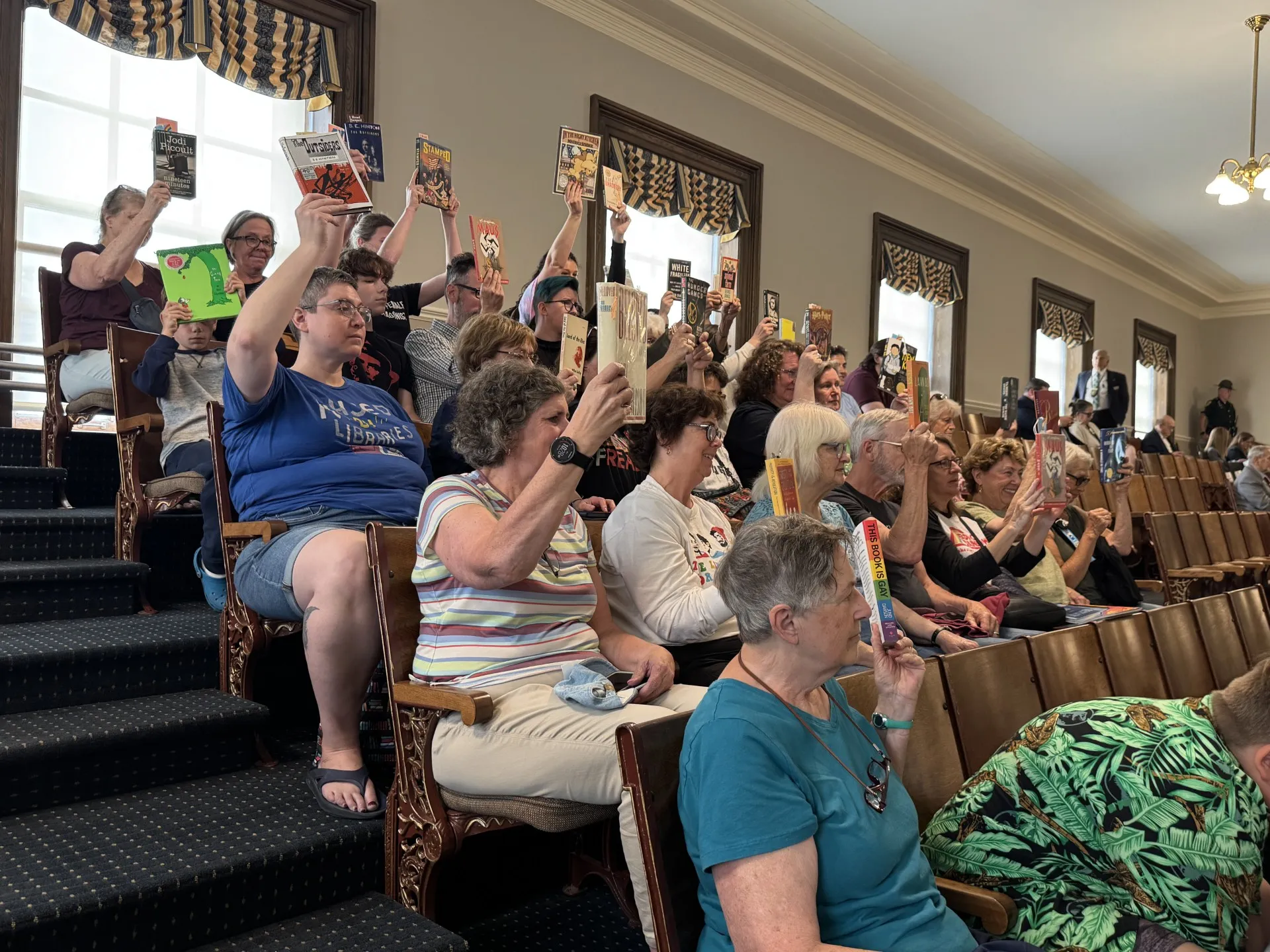 Protesters hold up copies of banned books in the New Hampshire House Gallery