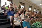 Protesters hold up copies of banned books in the New Hampshire House Gallery