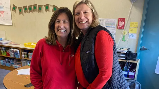 Two members pose for a picture wearing red