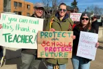 Members stand with signs that say "If you can read this thank a teacher," "Protect our Schools. Protect our Future."